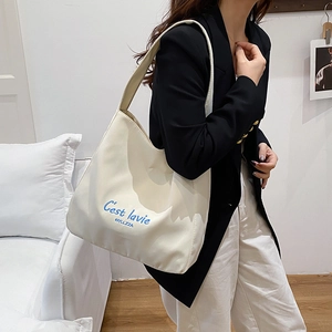 Off-white canvas tote bag with blue C'est lavie embroidery for women on a shoulder view