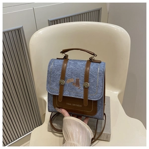 Detailed view of denim square bag featuring vintage brown leather straps and cat print