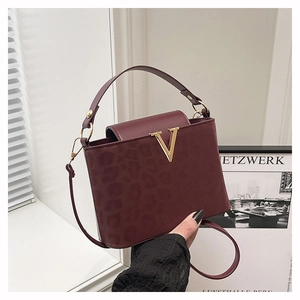 Gros plan du sac bandoulière bordeaux en cuir avec motif léopard et boucle en V doré