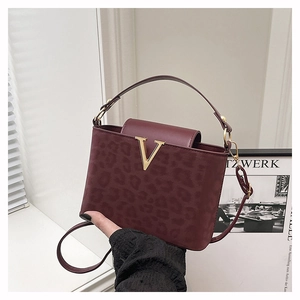 Detalle del bolso burdeos con relieve de leopardo y hebilla metálica en forma de V dorada