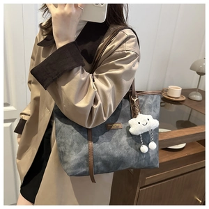 Detail of dark grey vintage tote with brown leather handles and cloud plush charm