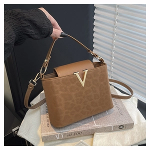 Detalle de bolso bandolera marrón de leopardo con logo V dorado y asa de cuero