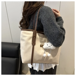 Close-up of retro contrast tote bag with premium leather handles and cute plush charm