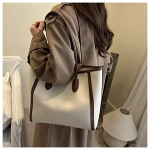 Detail of a minimalist tote bag in contrast colors paired with a classic trench coat