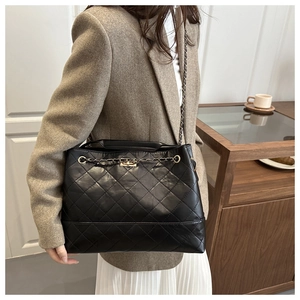 Detail of black quilted leather tote bag with elegant gold chain strap for daily commute