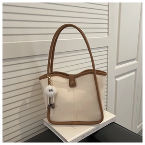 Minimalist beige shoulder bag with brown leather trim and cute plush monster charm
