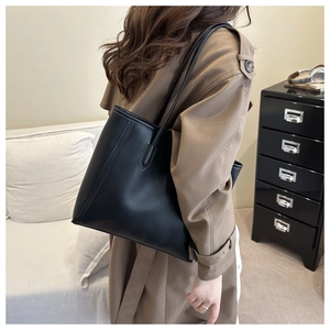 Minimalist black matte leather tote bag shown on shoulder from side-back view