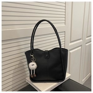 Close-up of a black minimalist tote bag featuring a cute white plush eye charm accessory