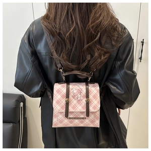 Detail view of pink plaid backpack with leather straps and cute cartoon dog illustration