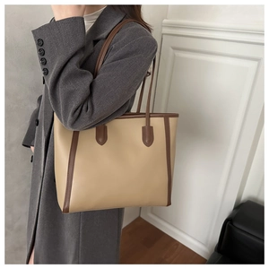 Detail of a large beige and brown tote bag showing the side view on a female model