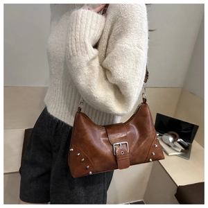Brown shell bag with silver rivets and metal buckle in a lifestyle fashion setting