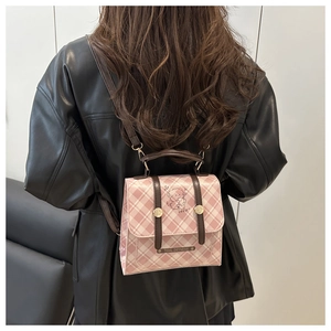 Detail of pink plaid PU leather backpack with dog print and metal brand name plate