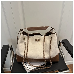 Detail of quilted canvas tote with brown leather trim and golden twist lock closure