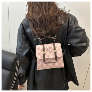 Detail of pink plaid backpack featuring cartoon dog illustration and leather straps