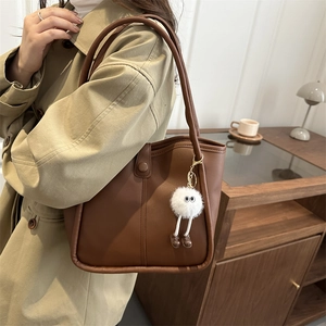 Minimalist brown leather underarm tote bag with a cute white plush charm on the side
