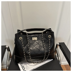 Detail of black quilted leather texture and gold twist lock on the large tote bag
