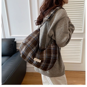 Detail of vintage plaid dumpling bag with power off patch worn by a model