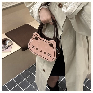 Detail showing creative cat-shaped pink handbag with brown leather handles and contrast trim