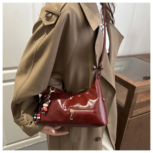 Detail of burgundy patent leather hobo bag with zip pocket and cute bull charm