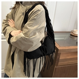 Détail du sac à bandoulière noir avec franges bohèmes et texture en daim de luxe