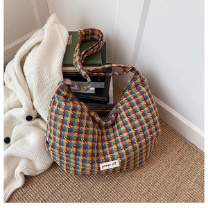 Detail view of colorful houndstooth crossbody bag with 'power off' woven label detail