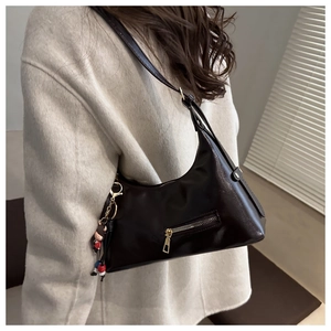 Close-up of a vintage leather crescent bag with smooth glossy finish and doll charm