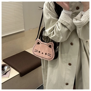 Chic cat-shaped crossbody bag in dusty pink worn by a model in a cozy indoor setting