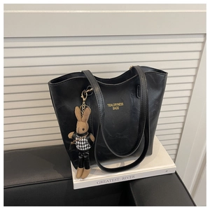 Detail of black textured PU tote bag with gold lettering and a stylish rabbit charm