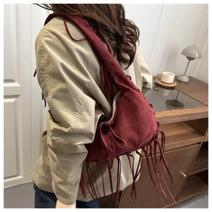 Détail du sac à bandoulière en daim bordeaux avec de longues franges au style bohème