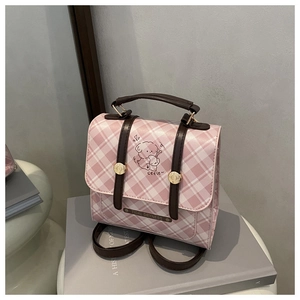 Detail of pink plaid satchel with bear illustration and metal decorative buckles
