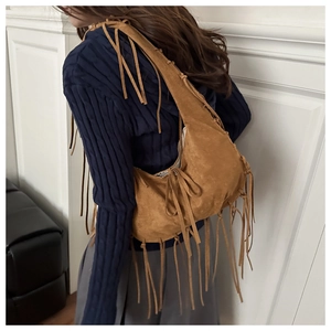 Gros plan d'un sac demi-lune en daim marron avec de longues franges de style bohème