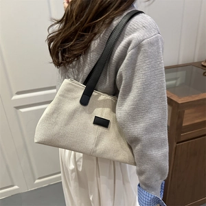 Minimalist beige canvas shoulder bag with black leather straps and stylish side stripes