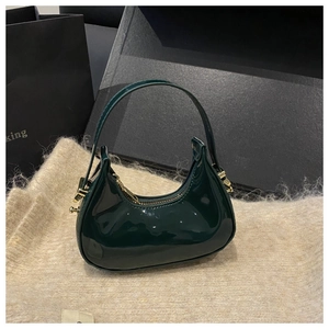 Close-up of green patent leather hobo bag with gold zipper on knit fabric background