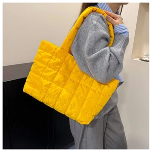 Detail of bright yellow quilted tote bag with wide shoulder strap in lightweight nylon