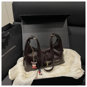Detailed view of deep brown hobo bag with gold zippers and a cute cow charm in a gift box