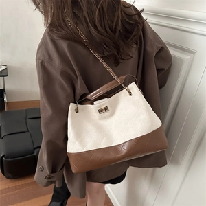 Chic quilted beige and brown leather tote bag with gold chain strap worn by a model