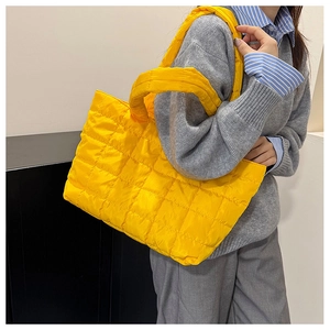 Quilted bright yellow puffy tote bag showing padded shoulder straps and soft texture