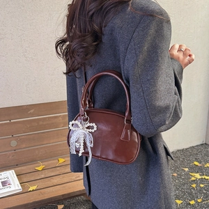 Brown retro crossbody bag with pearl bow and lace charm in a warm winter scene