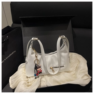 Detail view of white leather shoulder bag with zipper and cow charm in a gift box