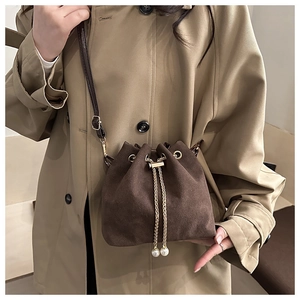 Detailed shot of brown frosted bucket bag featuring gold chain and pearl drawstring charms