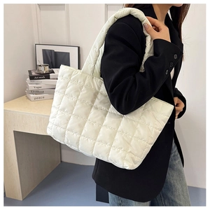 Detailed side view of a quilted puffer tote bag with wide shoulder straps on a person