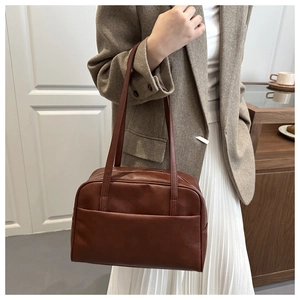 Detail of a dark brown vintage bowling tote bag worn with a casual blazer outfit