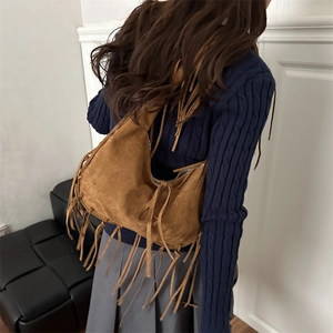 Sac fourre-tout marron en daim avec franges porté par un mannequin de profil