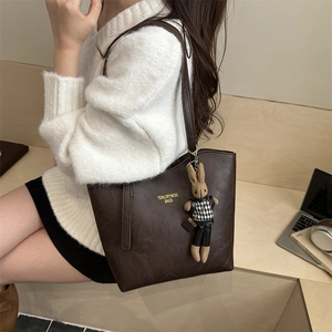 Brown faux leather tote bag with rabbit charm and gold logo for autumn casual style
