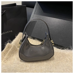 Close-up of grey glossy patent leather mini dumpling bag with gold zipper detail