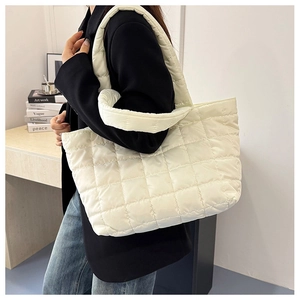 Detailed view of cream-white quilted tote bag worn by model in a minimalist setting