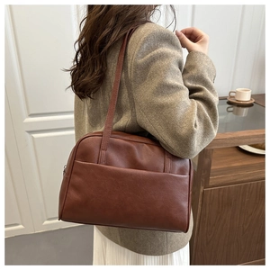 Close-up of a vintage dark brown leather shoulder bag with sleek minimalist texture