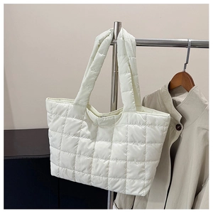 Detail of white quilted tote bag in padded nylon fabric hanging on a metal rack