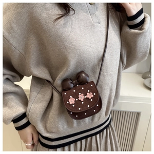 Close-up of children's brown polka dot crossbody bag with pink crochet flower details