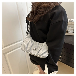 Detailed view of metallic silver hobo bag with pleated texture and silver butterfly buckle